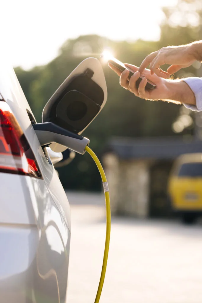 Businessman charging electric car at outdoor charging station